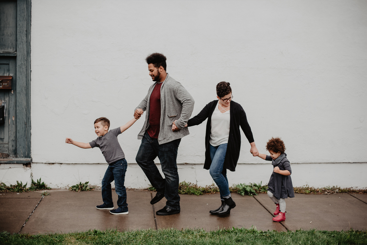 Family walking on sidewalk holding hands